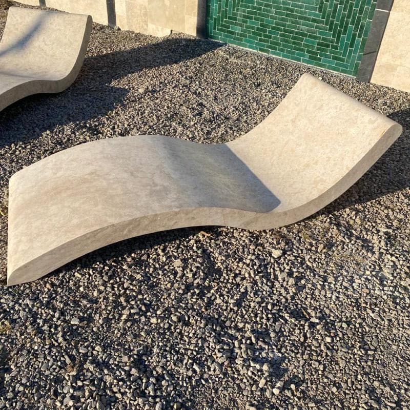 Deux transats monoblocs en pierre au profil galbé, en bord de piscine